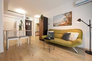 Uma sala de estar moderna com um sofá, poltronas, uma mesinha e um quadro na parede.