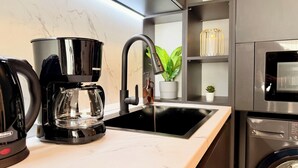 A modern kitchen with a coffee maker, sink, and stainless steel appliances. - Urban Heaven in Aviatiei Business Area (Bucharest)