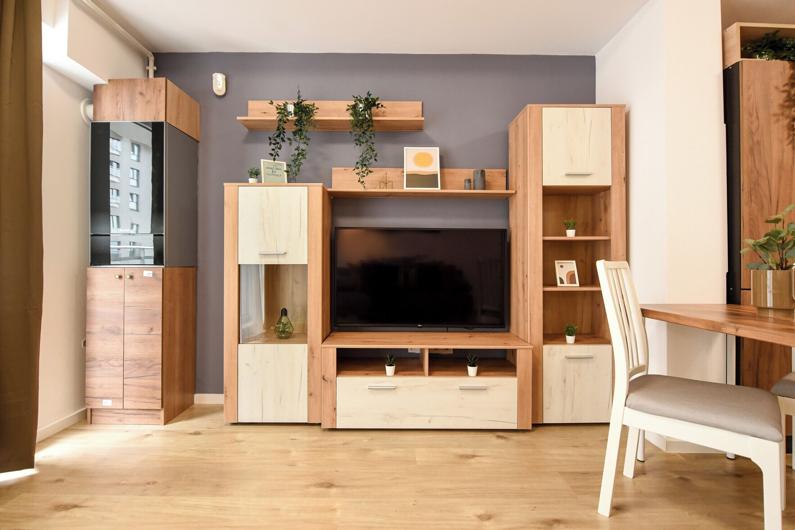 Una sala de estar moderna con televisor empotrado, armarios de madera y un comedor.