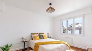 Quarto com cama, mesa de cabeceira, abajur, planta em vaso e janela com vista.