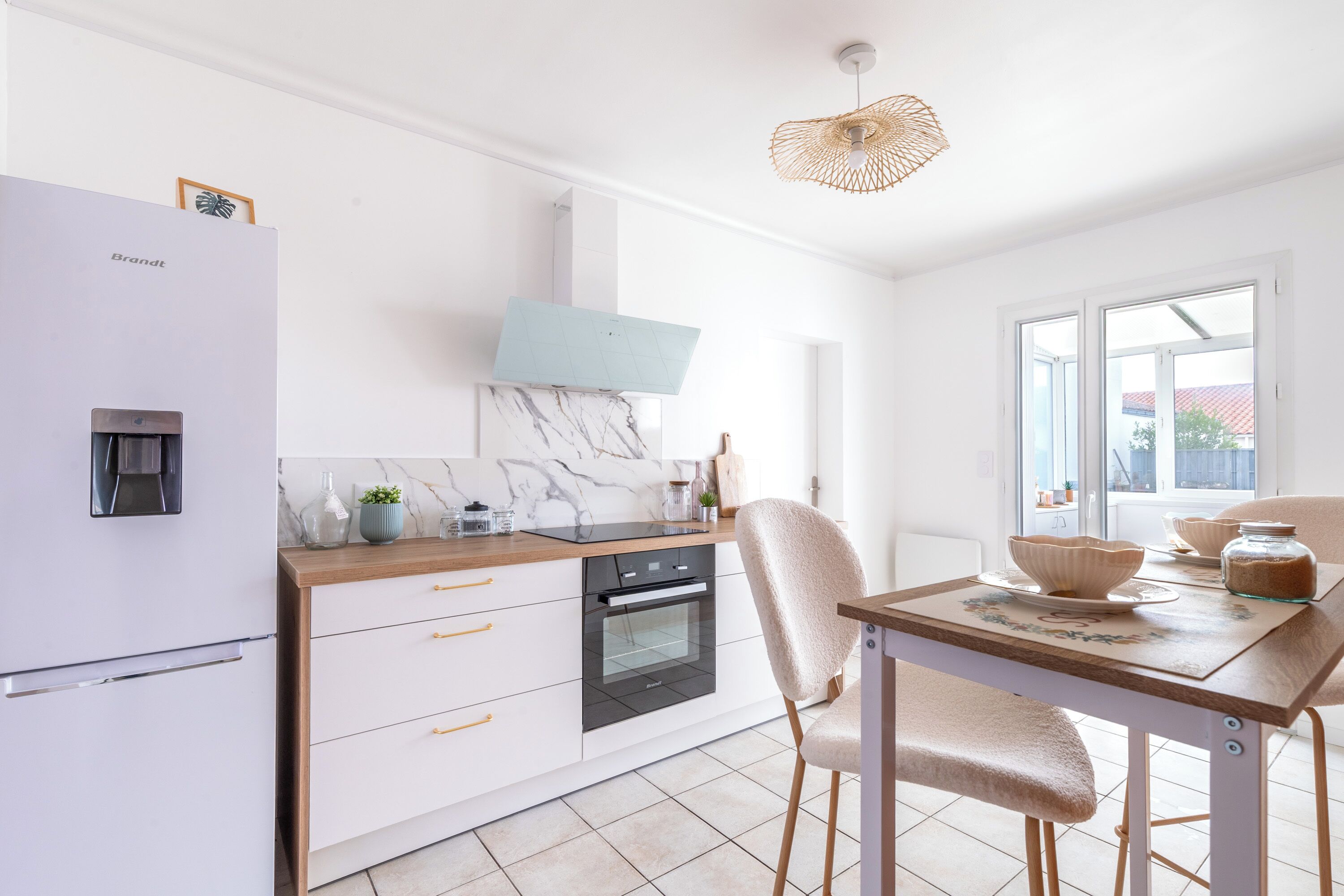 A modern kitchen with a refrigerator, oven, and dining table with chairs.