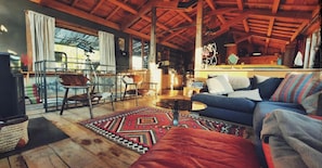 A cozy living room with a blue sofa, a patterned rug, and a wooden ceiling.