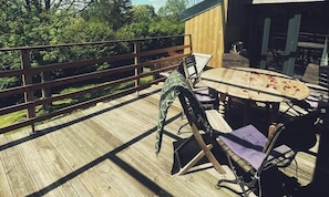 Una terraza de madera con mesa y sillas, una cerca de madera y un edificio al fondo.