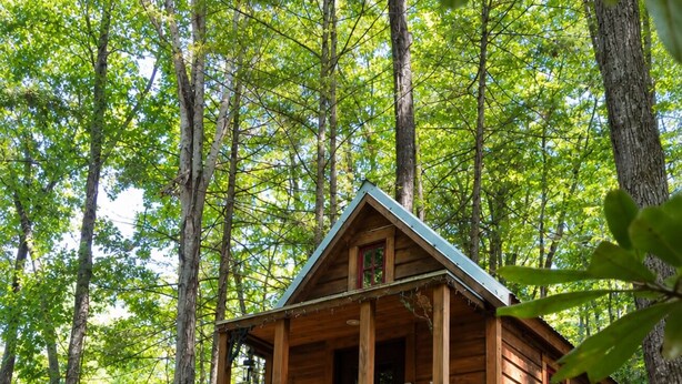 A wooden cabin with a porch, surrounded by rocks and trees.