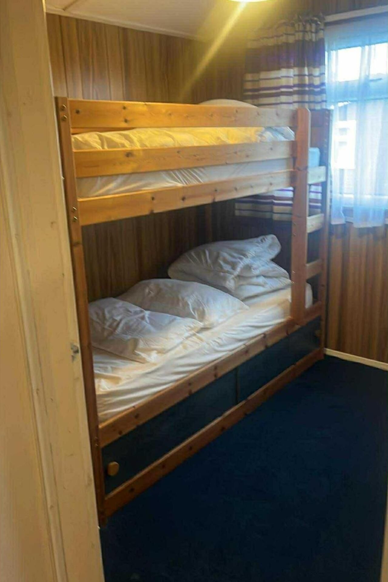 Una cama individual con estructura de madera y ropa de cama blanca.