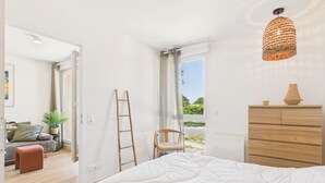 Una camera da letto con un letto, una cassettiera in legno, una lampada a sospensione e vista sull'esterno.