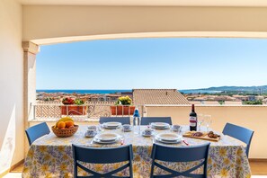 A table set for dining with a view of the sea and buildings. - Private owned Apartment with Spectacular Sea View in La Caletta Sardinia - 2 bedrooms 3 beds 1 bath (La Caletta)