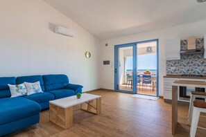 Ein Wohnzimmer mit blauem Sofa, einem Holztisch und einer Küchenzeile mit Blick.
