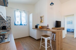 A compact kitchen with a microwave, toaster, and sink. A wooden bar counter with stools is adjacent to the kitchen. - Private owned Apartment with Spectacular Sea View in La Caletta Sardinia - 2 bedrooms 3 beds 1 bath (La Caletta)