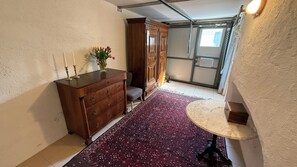 Un corridoio con un comò in legno, un tappeto decorato, un piccolo tavolino rotondo e un armadietto.