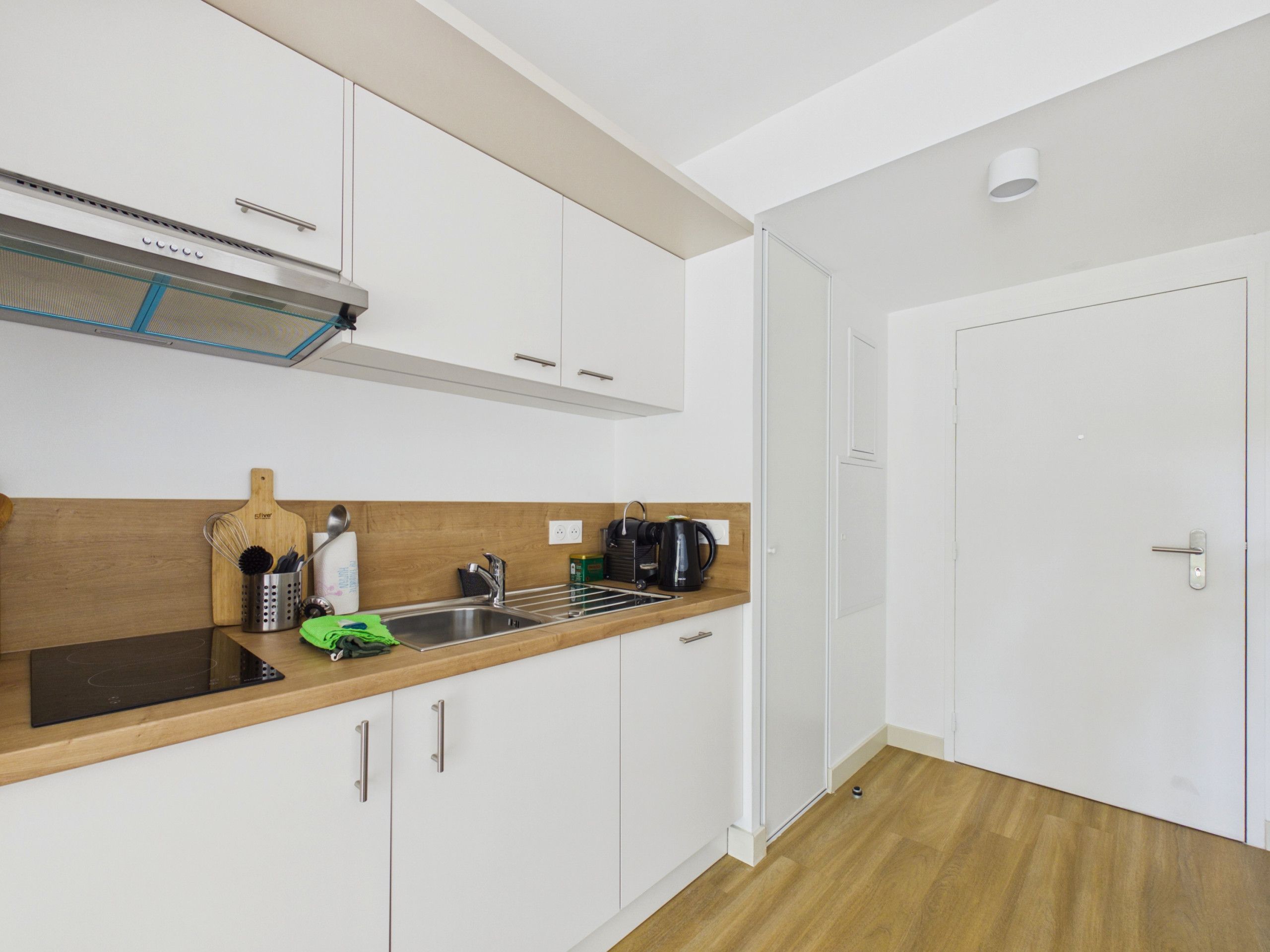 A modern kitchen with white cabinets, a wooden countertop, and a built-in stove.