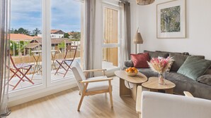 Un salon moderne avec un canapé, une table à manger et une chaise. Une grande fenêtre offre une vue sur l’extérieur.
