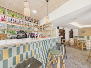 A bar area with shelves of liquor bottles, a coffee machine, stools, and a dartboard. - The Snap - 6 guests - shared pool (Biscarrosse)