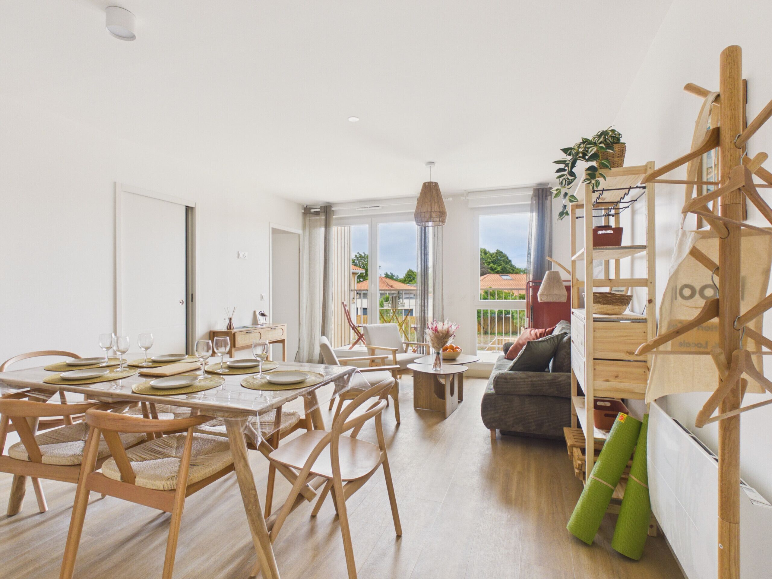 Un vaste espace de vie comprenant une table à manger pour quatre personnes, un canapé et un escalier doté d’une rampe en bois.