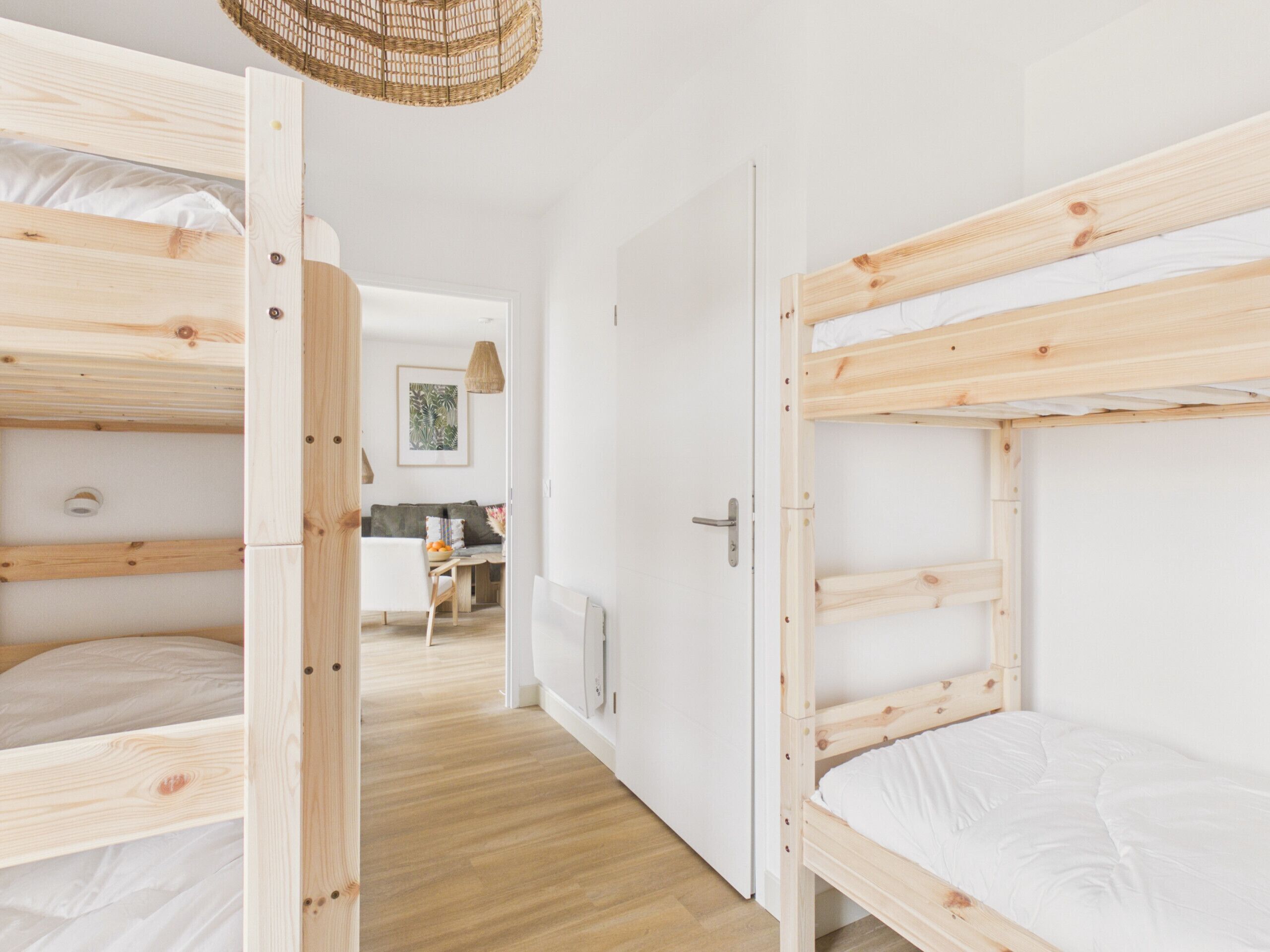 Een kamer met stapelbedden, een deur, een gang, een eethoek en een hanglamp.
