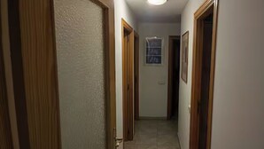 En smal gang med trædøre og en lampe i loftet.