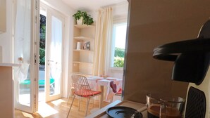 A room with a dining table, a chair, a coffee machine, and a view of an outdoor area with a pool. - Torrette "The First" - Pool-front relax within walking distance of everything (Peschiera del Garda)