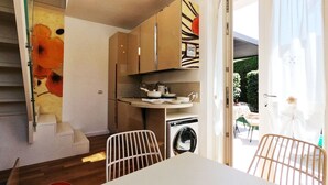 A modern kitchen with a dining area, a washing machine, and a staircase. - Torrette "The First" - Pool-front relax within walking distance of everything (Peschiera del Garda)