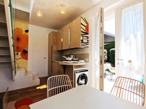 A modern kitchen with a dining area, a washing machine, and a staircase.