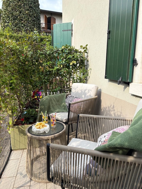 A patio with wicker furniture, a small round table, and a green door.