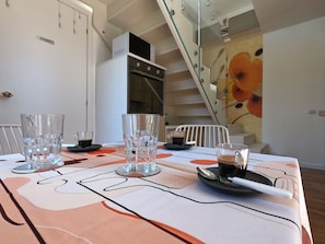 A dining area with a table set for two, a microwave, and a refrigerator in the background.