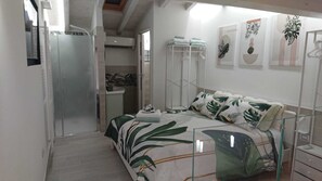 A bedroom with a bed, a wardrobe, a shower, and a bathroom.