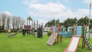 A playground with slides and climbing structures. - The Dorchester at Bay View (New Quay)