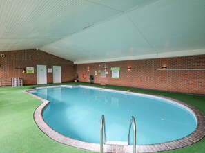 An indoor swimming pool with a brick wall, green artificial turf, and a ceiling with a ribbed pattern. - The Dorchester at Bay View (New Quay)
