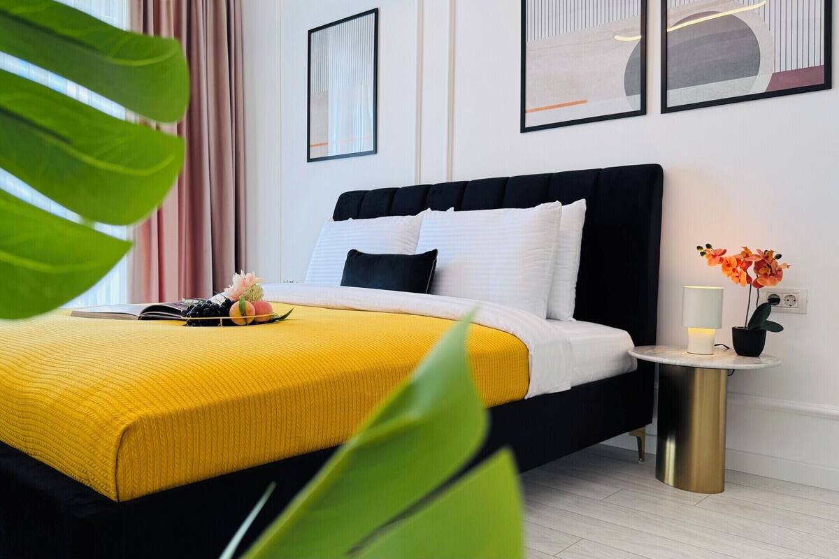 A modern bedroom with a bed, bedside table, and a potted plant.