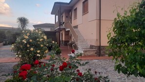 A two-story house with a staircase leading to the upper floor, a paved driveway, and a garden with flowers and shrubs. - 10 minutes from Lucca, 130 sq. m. apartment with garden, pets dom. allowed (Capannori)