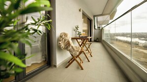 A balcony with a view of a river, a dining table with chairs, and a plant. - Great Apartments in Prime North Location (Bucharest)