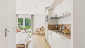 A modern hotel room with a bed, a dining area, and a kitchenette. - Le Fish - studio for 3 - shared pool (Biscarrosse)
