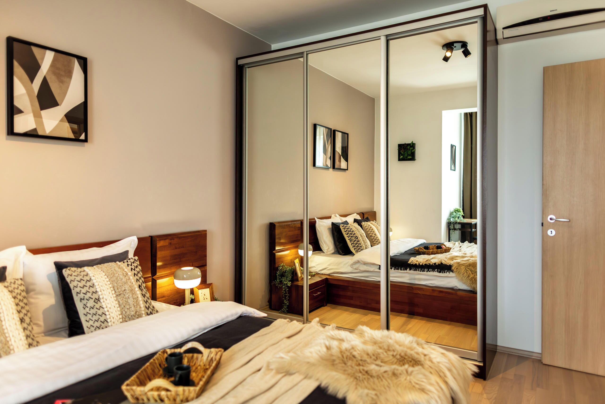 Ein Schlafzimmer mit Bett, Nachttischen, einem Spiegel, einem Kleiderschrank und einem Wandbild.