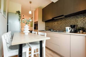 Una cocina moderna con una mesa de comedor, sillas y una cafetera.