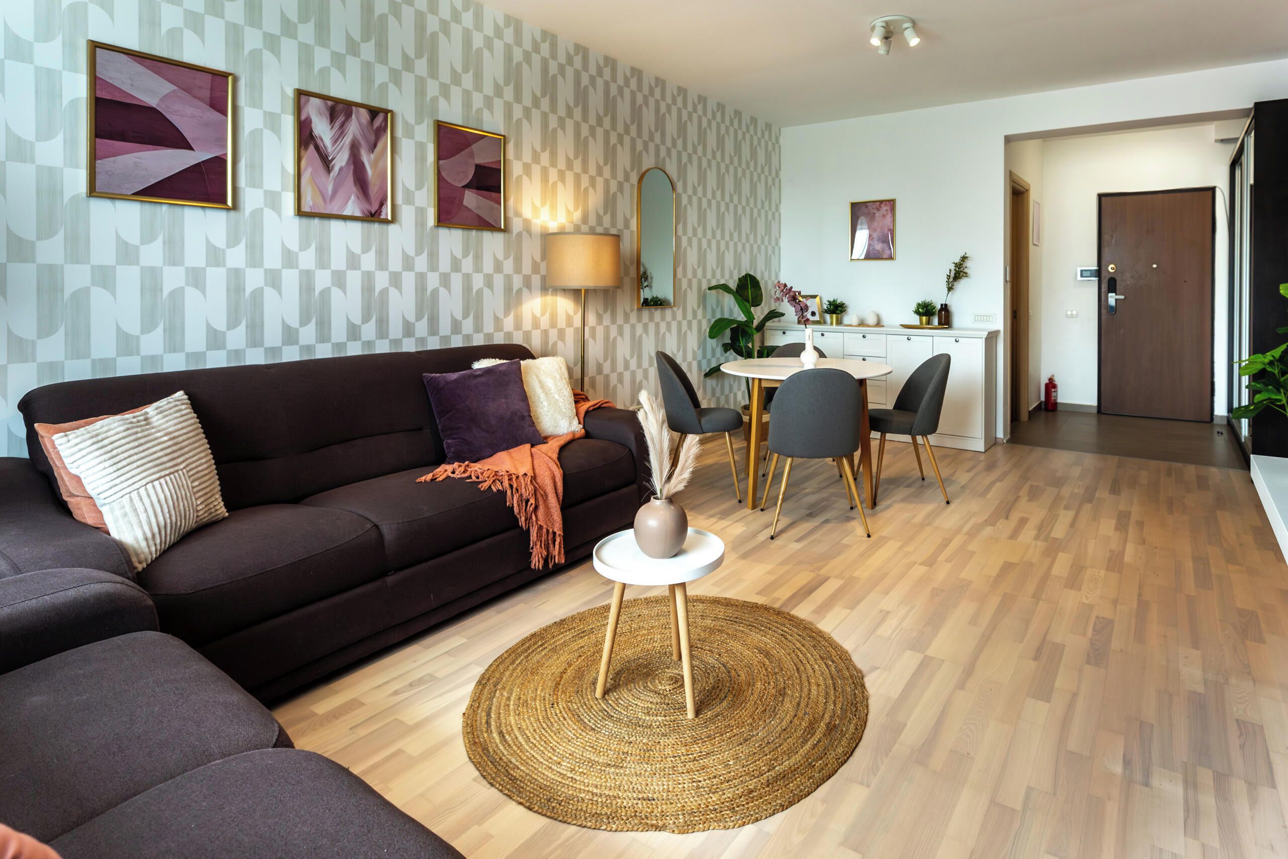 Een moderne woonkamer met een bank, een rond bijzettafeltje en een eethoek met stoelen en een tafel.