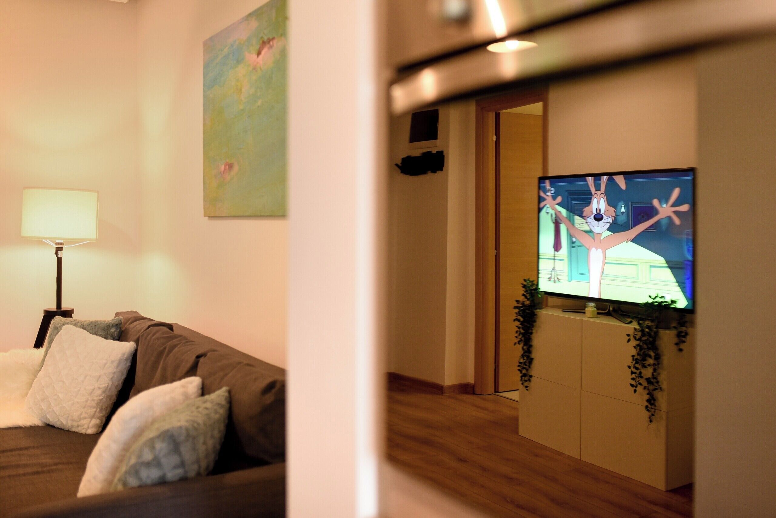 Un salon avec un canapé, un téléviseur et un tableau accroché au mur.