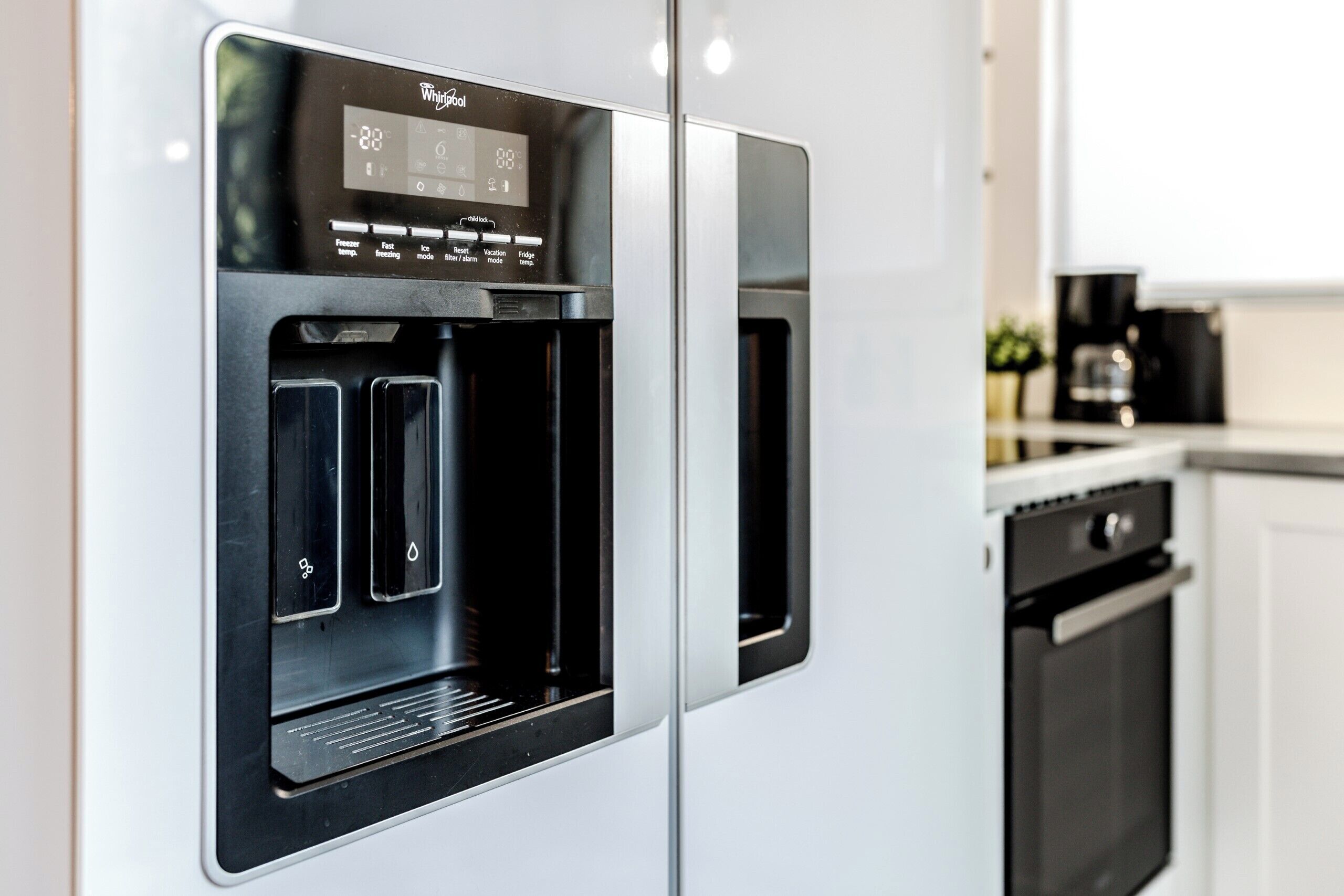 A modern kitchen with a built-in water dispenser, a coffee maker, and a dishwasher.