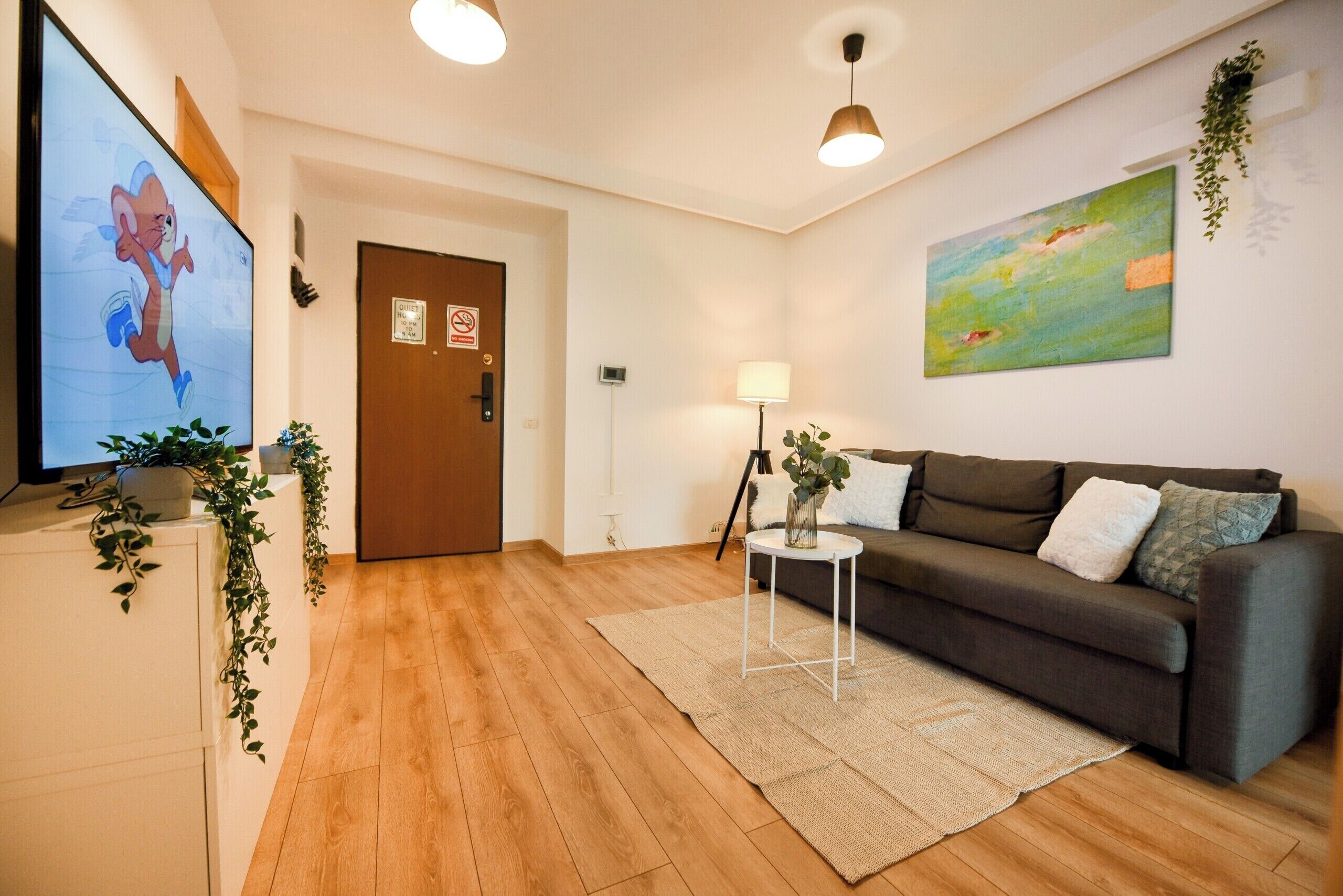 A living room with a television, a sofa, a lamp, and a painting on the wall.