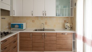 Una cocina con armarios blancos, un microondas, una estufa y un lavamanos.