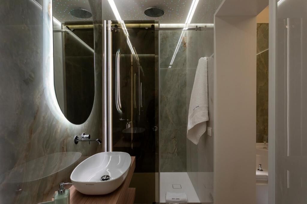 Une salle de bain moderne avec une douche à parois de verre, un lavabo blanc et un mur en marbre.