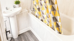 A bathroom with a white sink, a mirror, a potted plant, and a shower curtain with a geometric pattern. - Room-twin Single Bedroom Perfect for con (Wolverhampton)