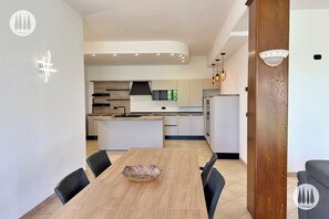 Une cuisine moderne dotée d’un îlot central, d’un éclairage encastré et d’un coin repas avec une table et des chaises en bois.