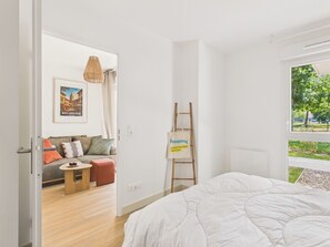 Une chambre à coucher moderne avec un lit, une échelle en bois, une petite table, un canapé et un luminaire suspendu.