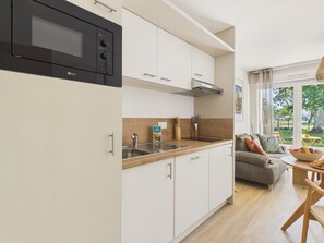 A modern kitchen with white cabinets, a black microwave, and a wooden countertop. - La Planche Malibu - apartment for 4- shared pool (Biscarrosse)
