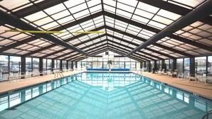 Una piscina interna con soffitto alto, pannelli di vetro trasparenti e indicatore di profondità di circa 90 centimetri.