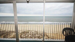 Un balcone con vista sulla spiaggia, una sedia e un tavolo.