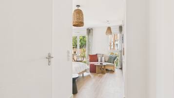 A modern interior with a wooden floor, a sofa with cushions, a small round table, and a hanging light fixture.