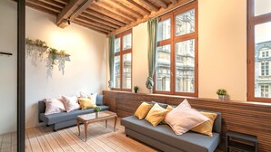 A room with a wooden ceiling, two sofas with cushions, a coffee table, and large windows with curtains. - Stylish Duplex for 6 in Antwerp (Antwerp)