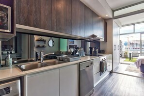 Eine moderne Küche mit Edelstahlgeräten, einem Geschirrspüler und einem großen Fenster mit Blick auf die Stadt.