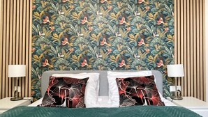 Een hotelkamer met een bed, twee nachtkastjes, een wand met een bloemenpatroon en een groene sprei.